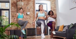 A group of women doing the high knees exercise in a living room.