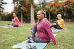 A group of women doing yoga at a park. They have overcome barriers to physical activity for women and girls. 