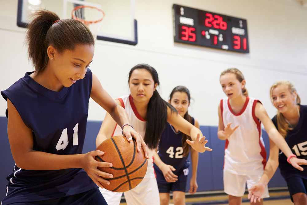 A group of teenage girls playing basketball.