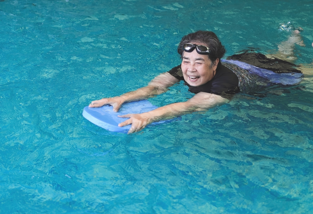 Une femme souriante nage dans une piscine. 