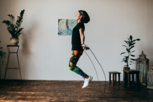 Une femme utilise une corde à sauter dans un salon. 