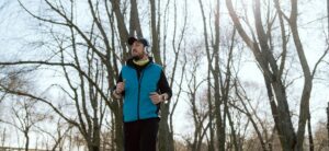 Un homme faisant son jogging sur une route avec des arbres derrière lui.