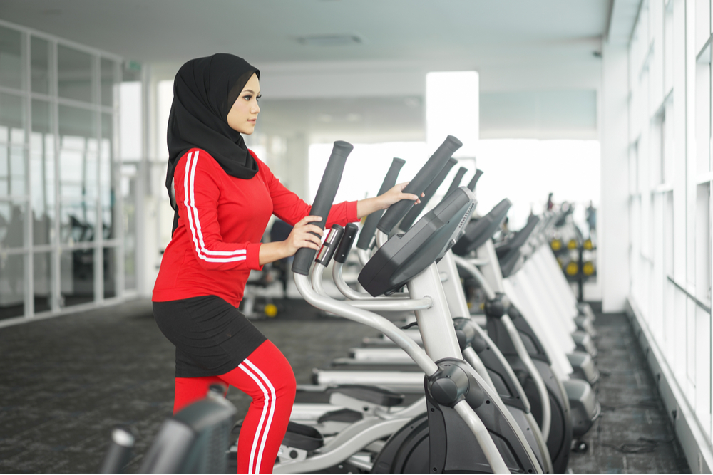 A woman wearing a hijab using an elliptical. She knows how to stay active during Ramadan. 