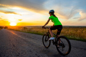 A woman cycling on a dirt road. 