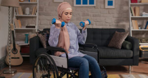 A woman in a wheelchair lifting dumbbells in a living room. Hormones affected by exercise.