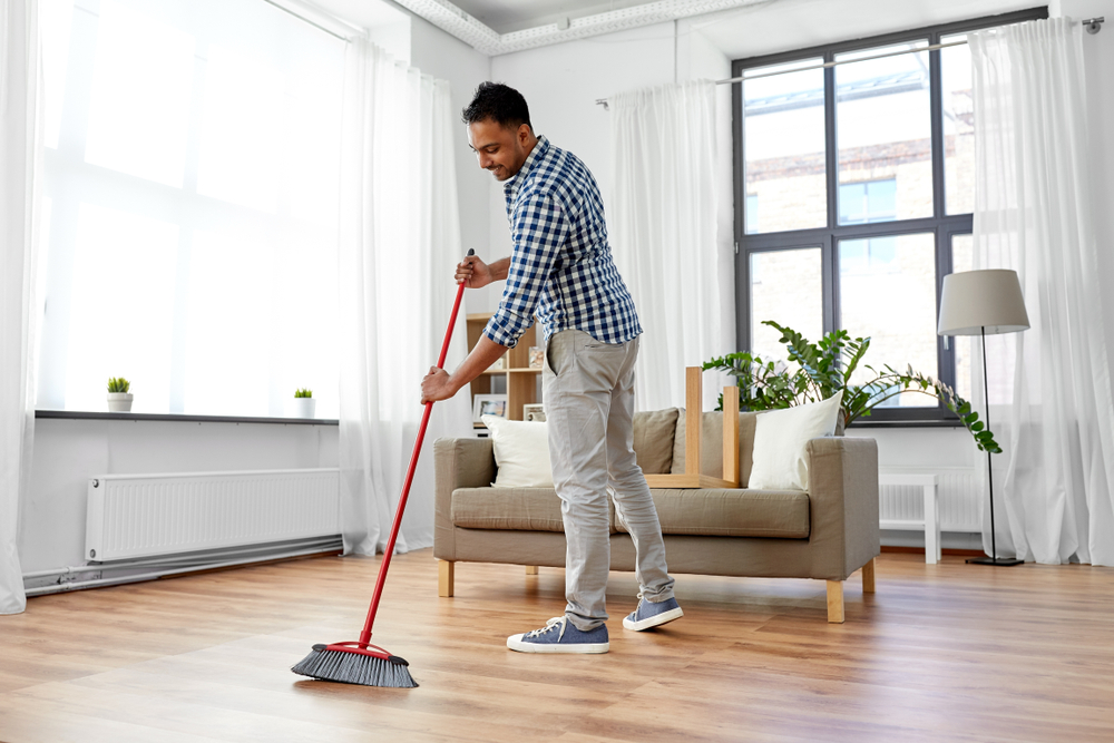 A man sweeping a living room floor.