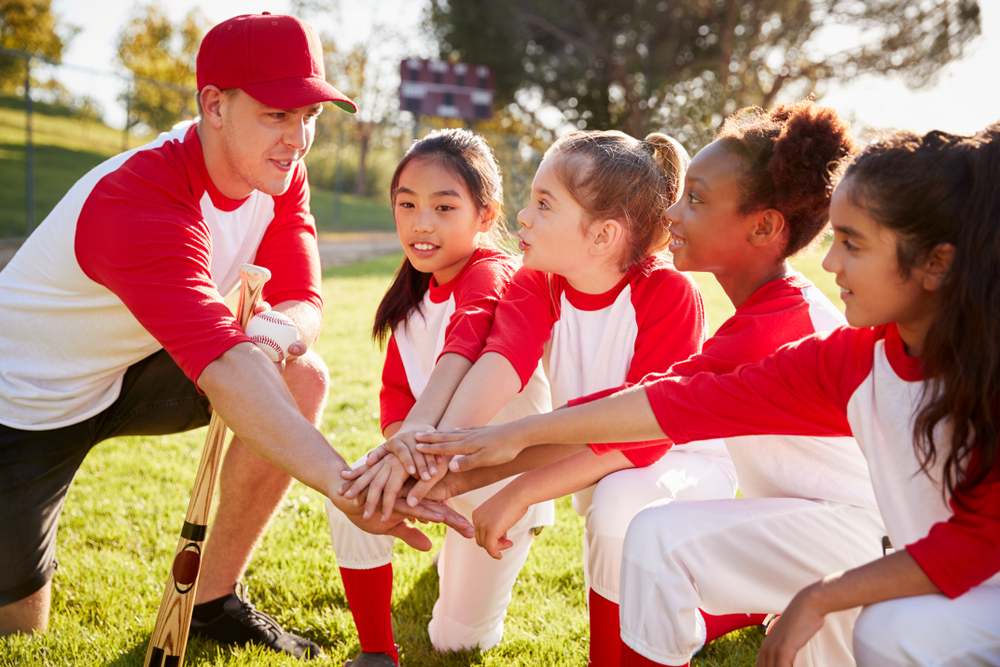 A coach holding hands with soccer players. 