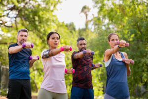 A group of people working out with dumbbells in a park.