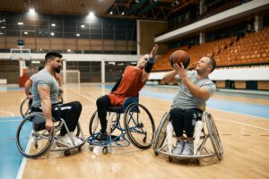 Un groupe d’hommes jouant au basketball en fauteuil roulant sur un terrain intérieur. 