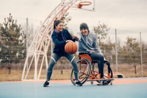 Un homme en fauteuil roulant joue au basket avec une femme debout. 