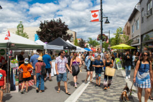 A group of people walking through a street festival, one of many summer 2023 bucket list ideas. 