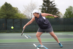 A person playing pickleball, a so-called fitness fad, on an outdoor tennis court.