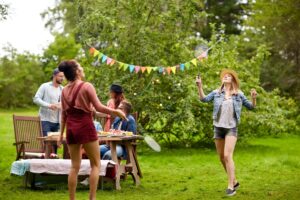 Deux femmes jouent au badminton sur un terrain près d’un groupe de personnes qui pique-niquent.