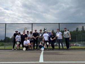 Un groupe de personnes debout sur un terrain de tennis avec des raquettes de tennis léger.