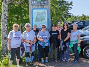 A group of people from the community who won the Community Challenge standing in a parking lot beside a forest.