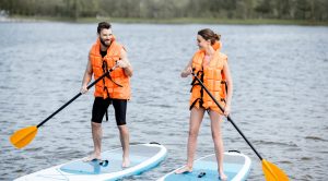 Un homme et une femme pratiquent la planche à pagaie sur un lac.