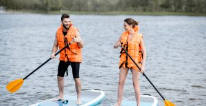 A man and woman paddleboarding on a lake.