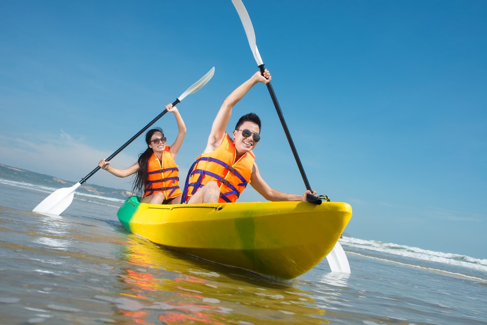 A man and woman tandem kayaking in an ocean.