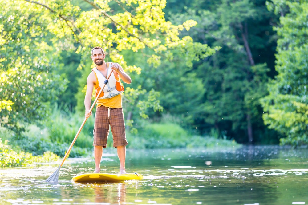 A man paddleboarding in a river. 