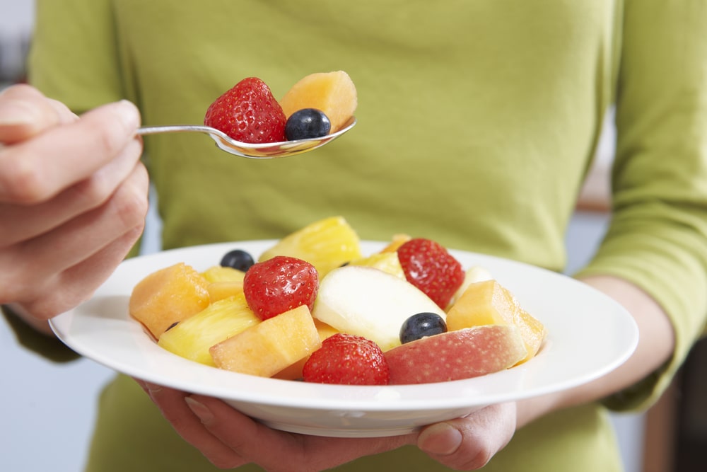A person holding a plate of fruit. 
