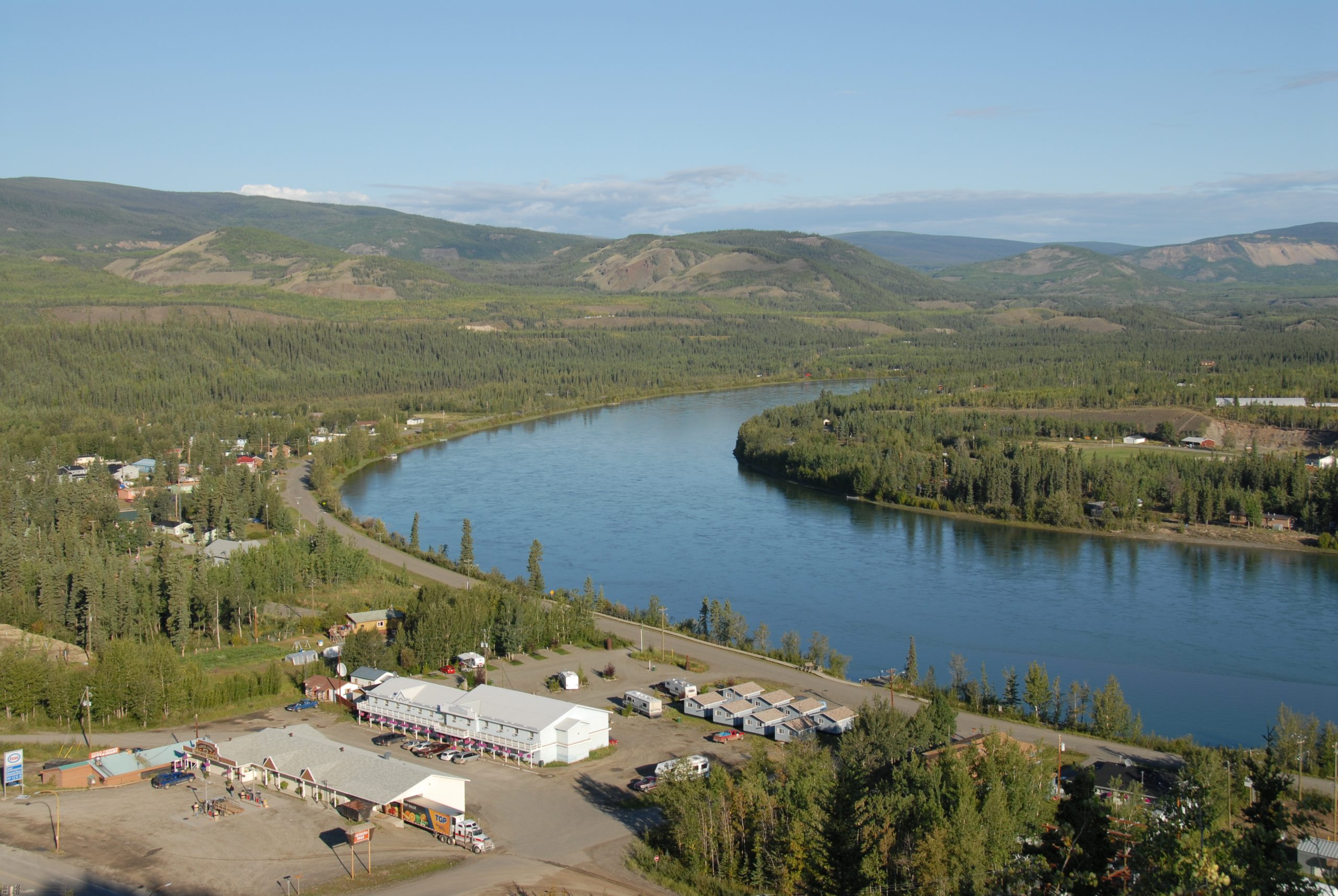 A river surrounded by mountains and houses in Carmacks, one of many hidden Yukon tourist attractions.