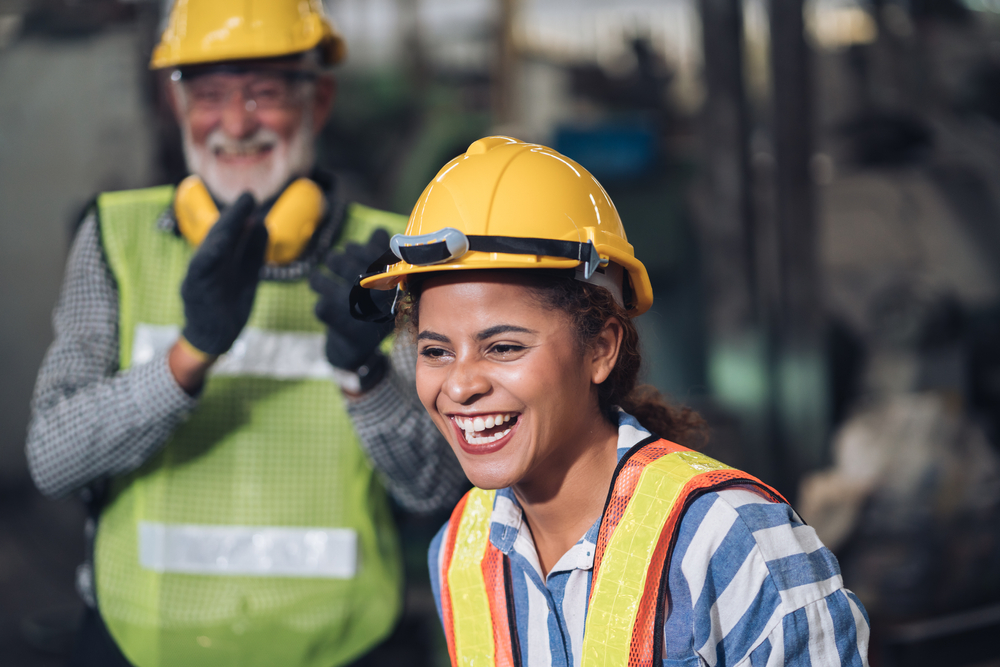 Two smiling construction workers wearing hard hats and safety vests.