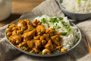 A plate topped with cashew chicken, rice and green onions.