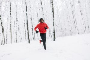 A person running in a snow-covered forest.