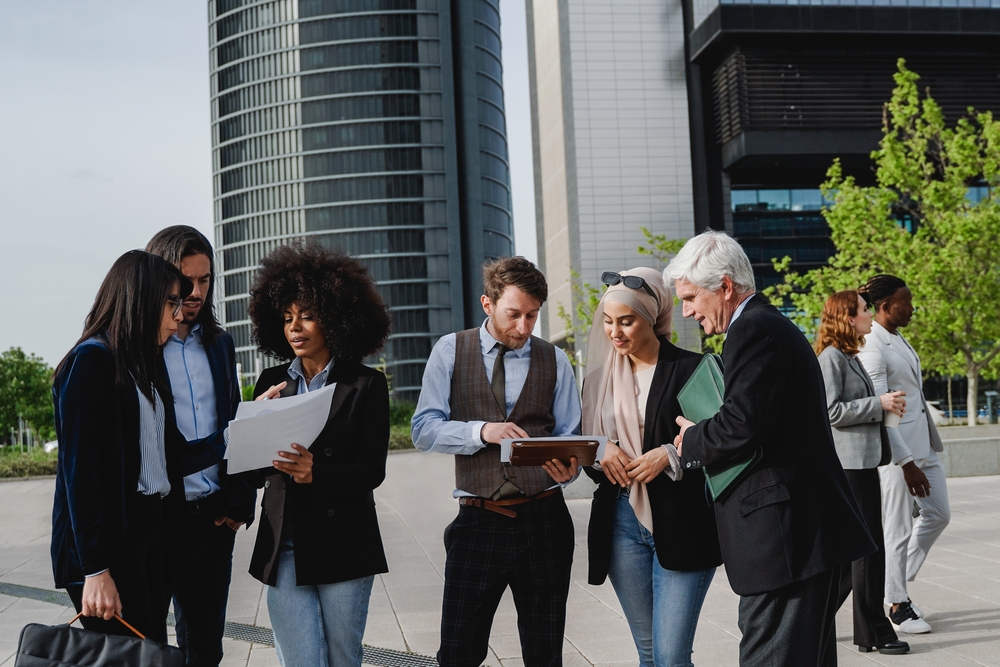 A group of office workers standing and talking outdoors. 