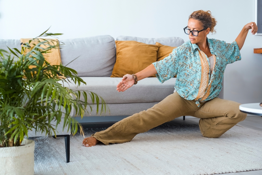 A woman practicing tai chi in a living room. 