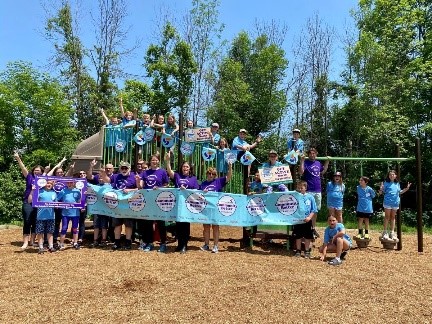 Large group of North Grenville individuals hold Community Challenge Banner at a park.