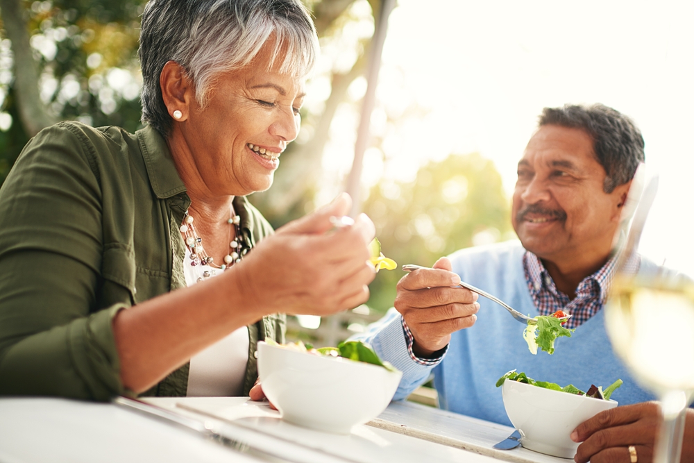 An older woman and man eating salads outdoors to help prevent and manage type 2 diabetes.