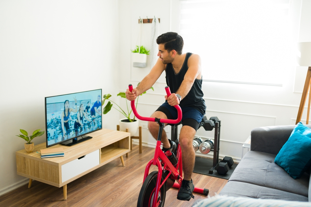 Un homme regarde la télévision sur un vélo stationnaire. 
