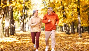 A man and woman jogging on a nature trail in autumn.