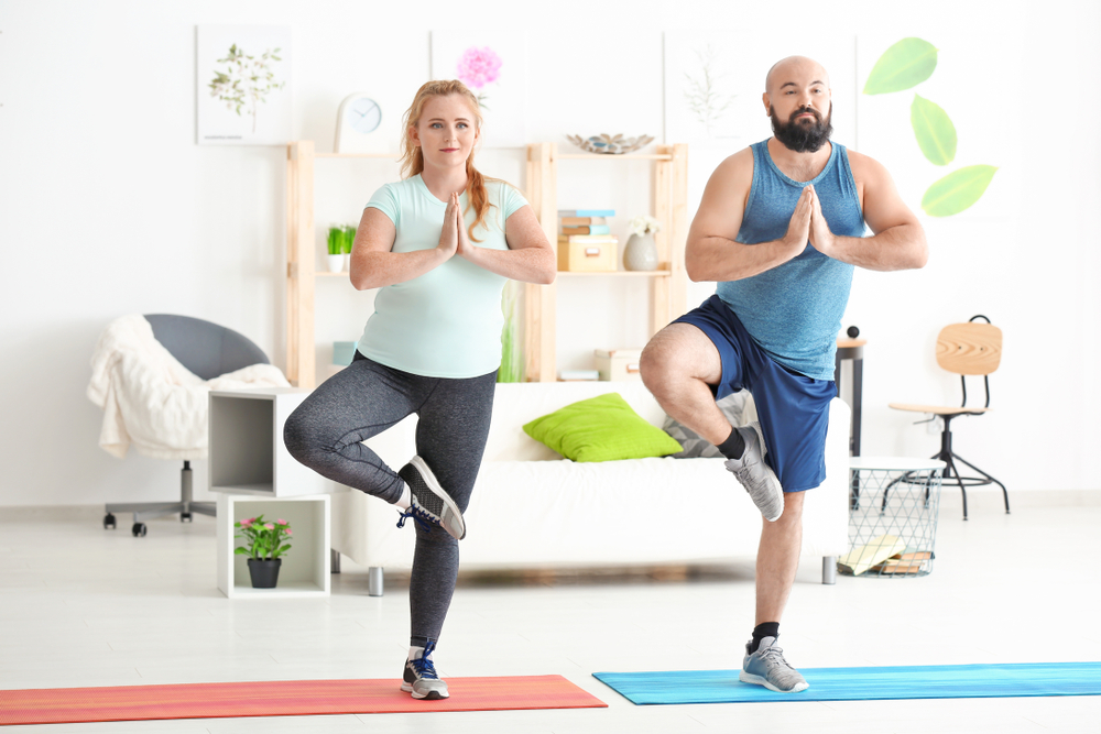 A man and woman doing yoga in a living room.