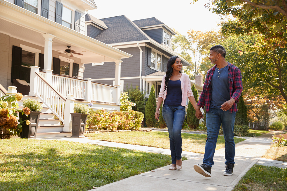 A man and woman walking in a suburban neighbourhood. 