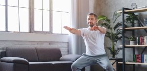 Un homme fait des flexions sur une jambe sur un canapé dans un salon.