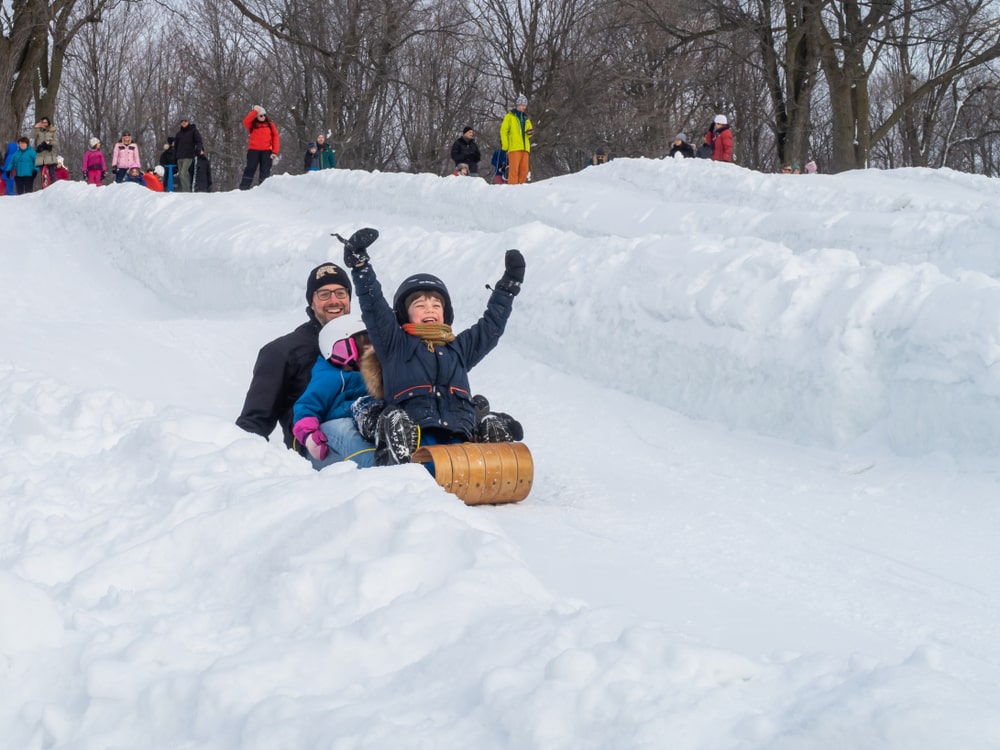 A father and his two kids tobogganing.