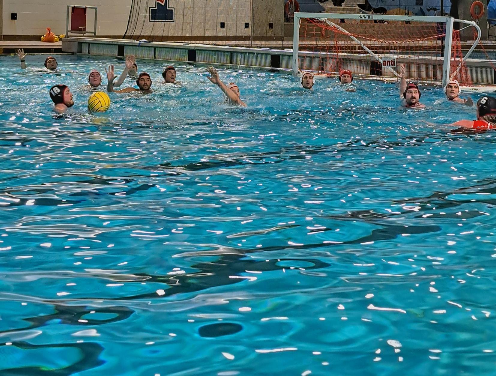 Des personnes jouent au water-polo dans une piscine intérieure.