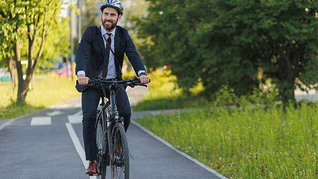 man with suit on riding a bike in park path