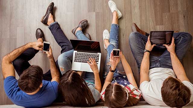 overhead view of young people sitting on the ground using mobile devices