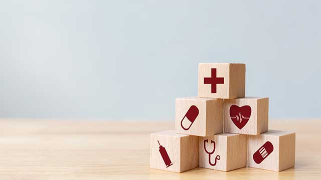 wooden blocks with health symbols like heart, cross, pill etc