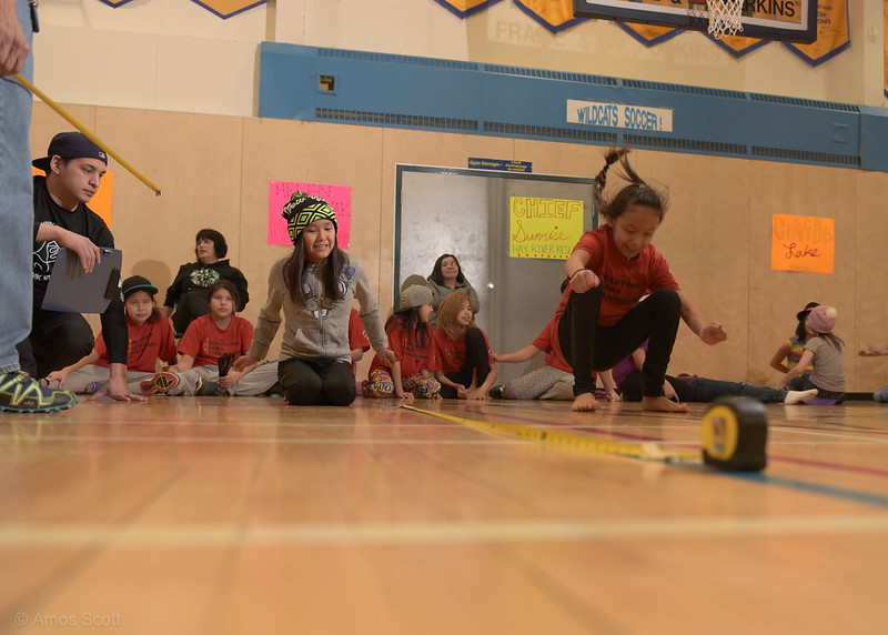 Girls playing the Inuit game called kneel jump in a gymnasium. 
