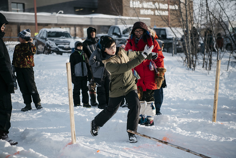 Un groupe d’enfants s’adonne au jeu déné du serpent des neiges sur un terrain enneigé. 