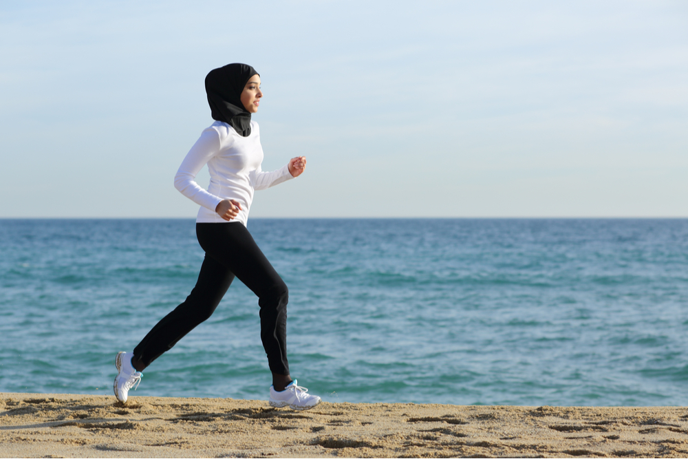Une femme musulmane fait du jogging sur une plage pendant le ramadan.
