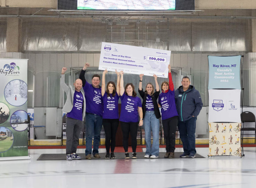 Residents of Hay River, Northwest Territories holding up an over-sized cheque on an indoor ice rink. Residents of Hay River, Northwest Territories holding up an over-sized cheque on an indoor ice rink.
