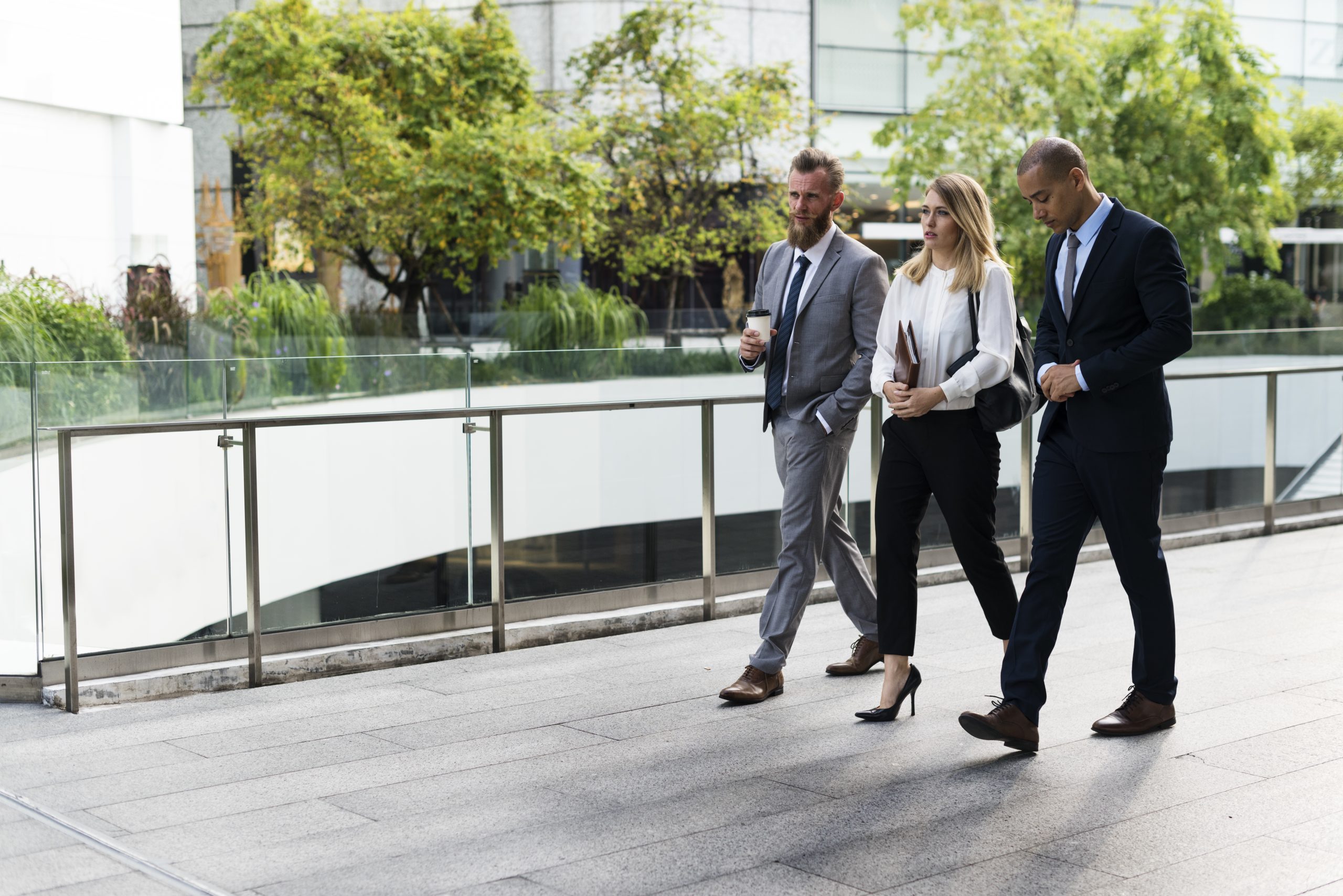 A group of people in business clothes walking on the sidewalk. A group of people in business clothes walking on the sidewalk.