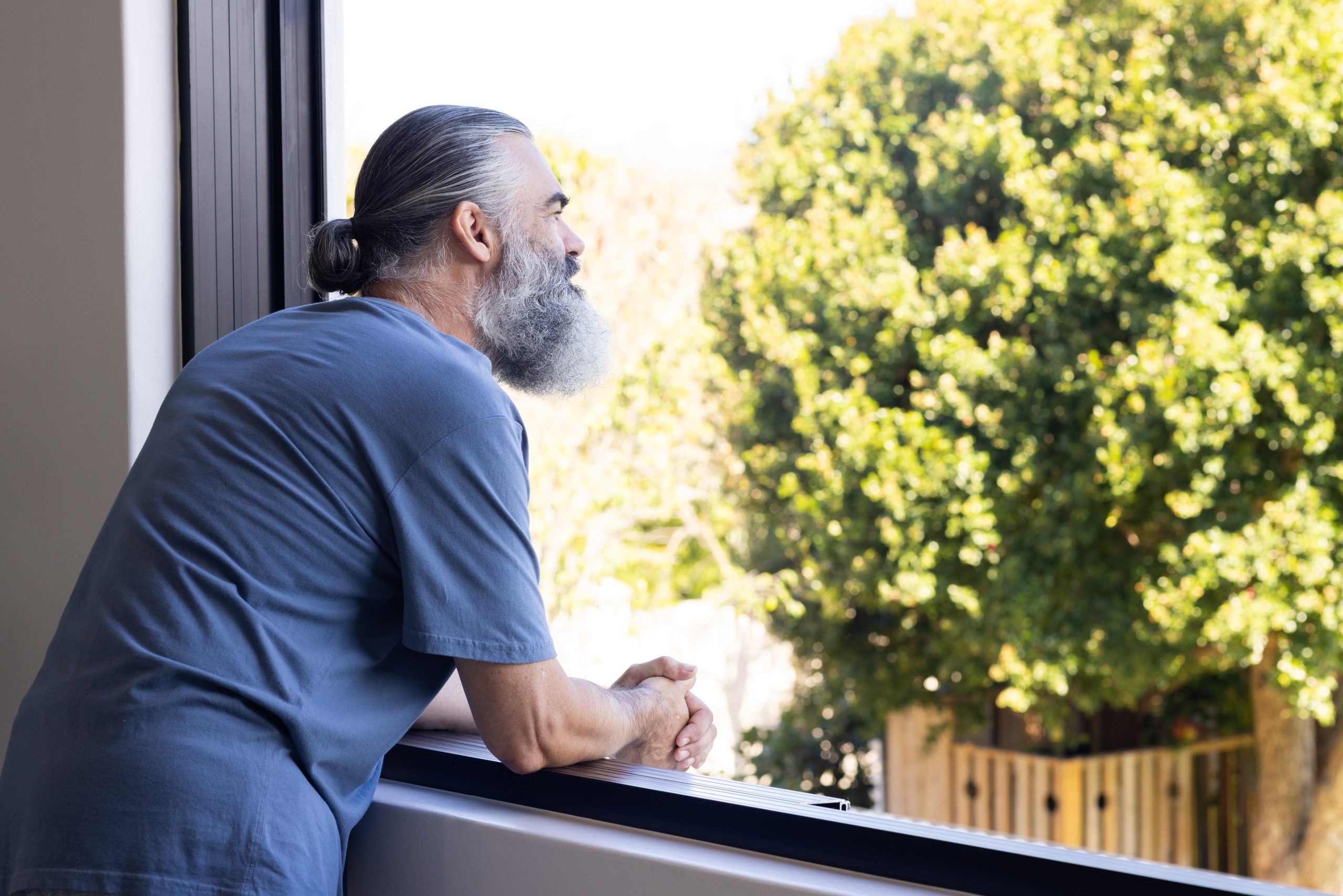 A man looking out a window on a sunny day. A man looking out a window on a sunny day.
