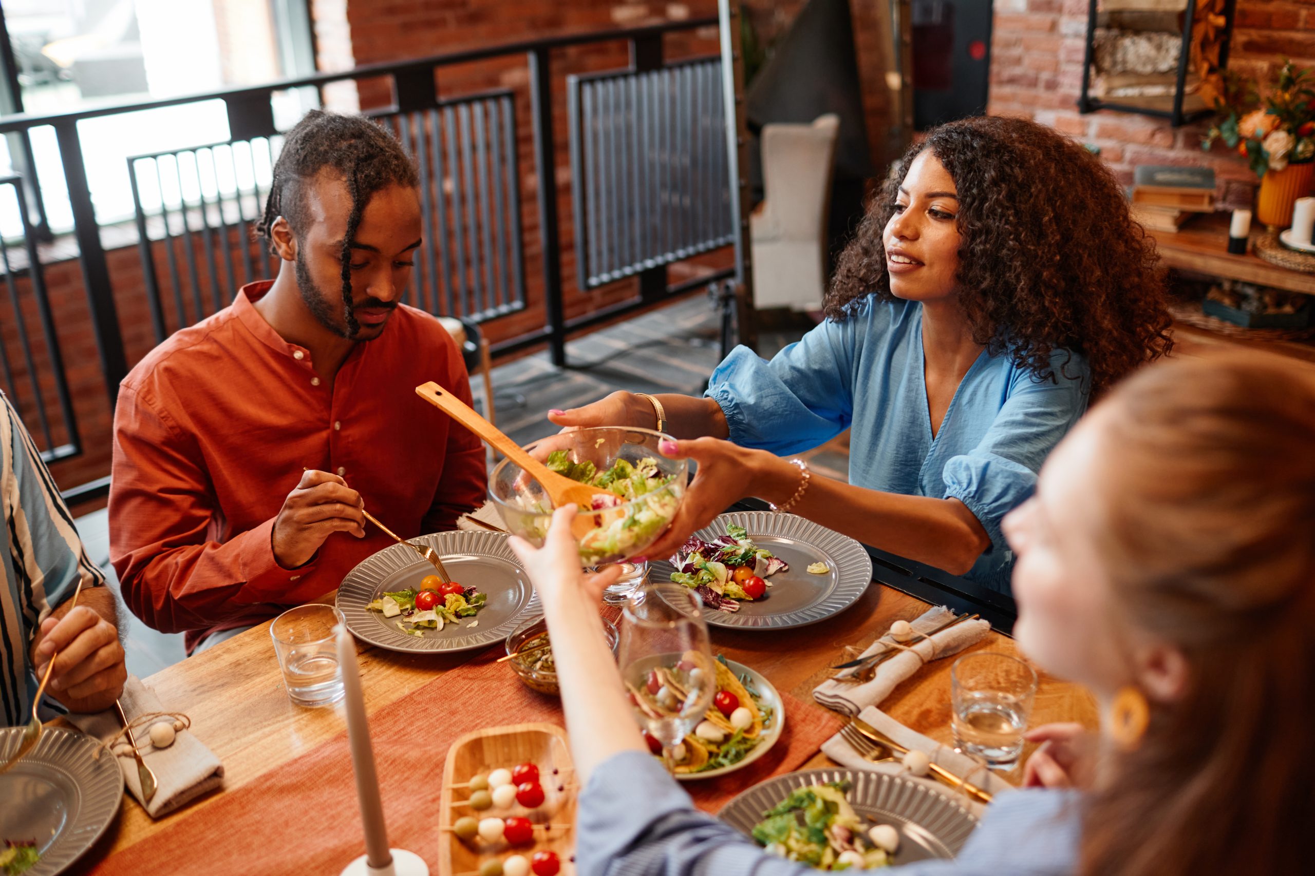 Un groupe de personnes assises autour d’une table mange de la salade.  