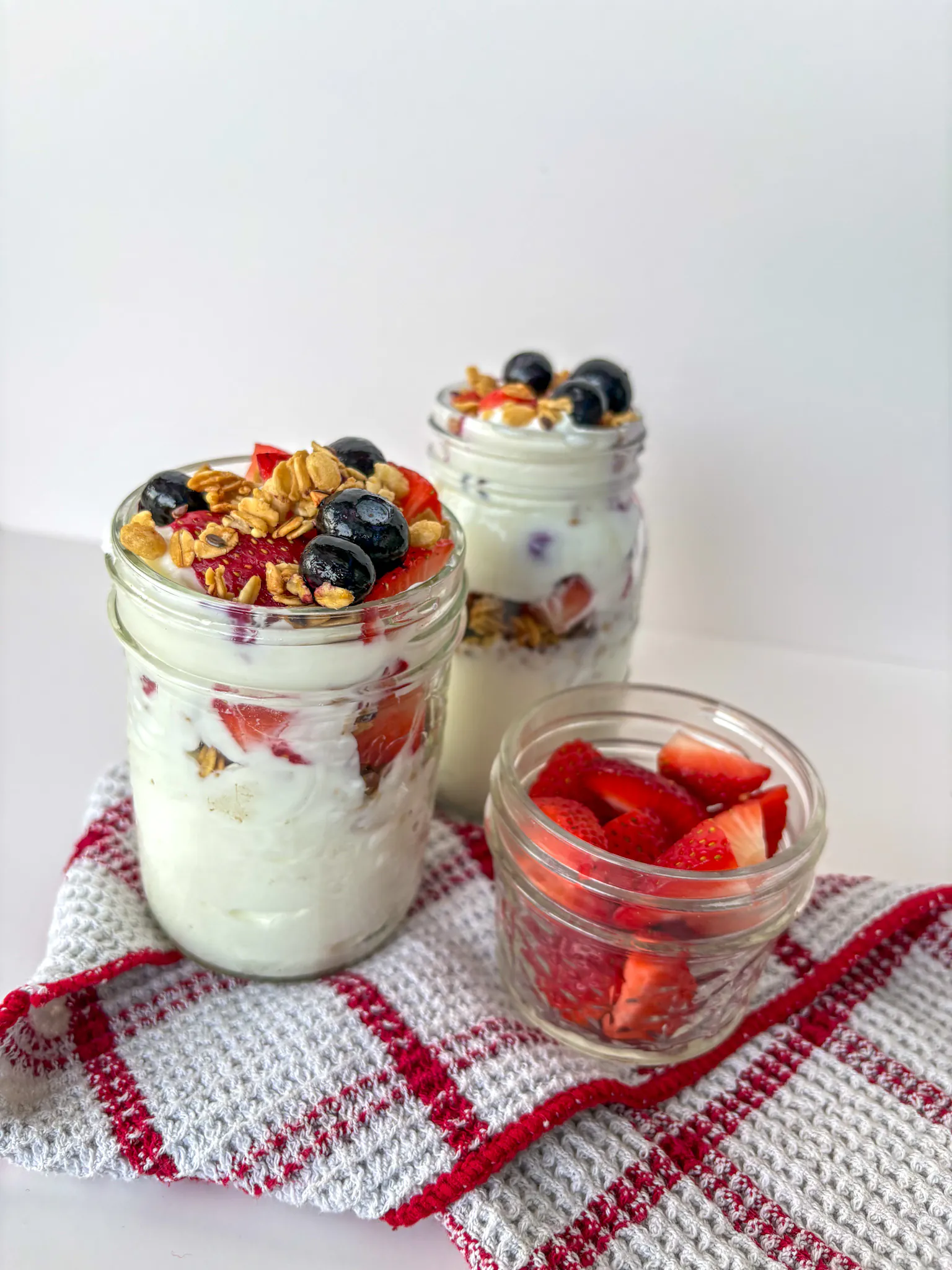 Parfaits au yogourt, aux petits fruits et au granola servis en pots sur une table. Recette du mois pour vous aider à bouger : Parfait au yogourt, aux petits fruits et au granola